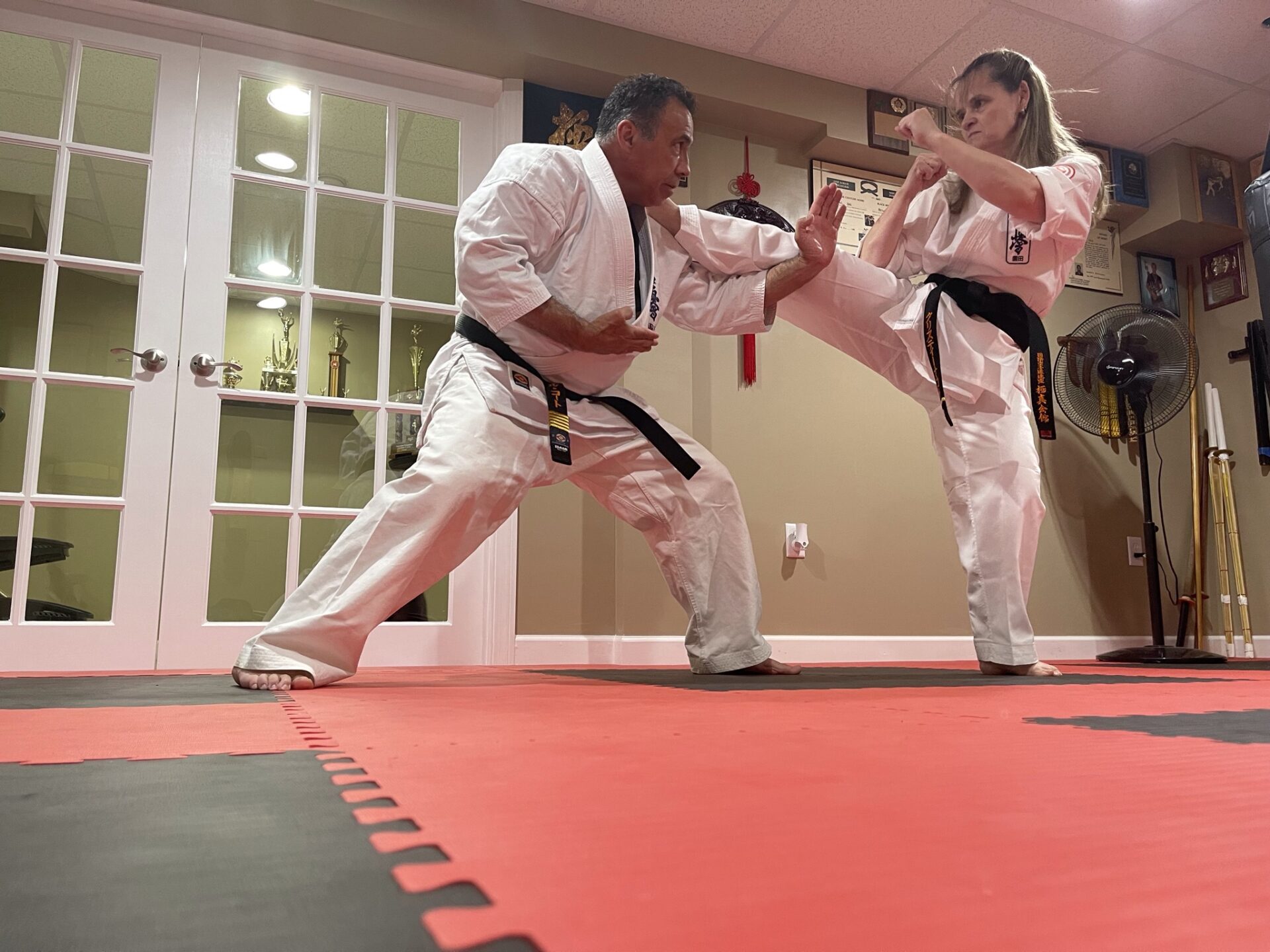 Two people practicing martial arts in a gym.