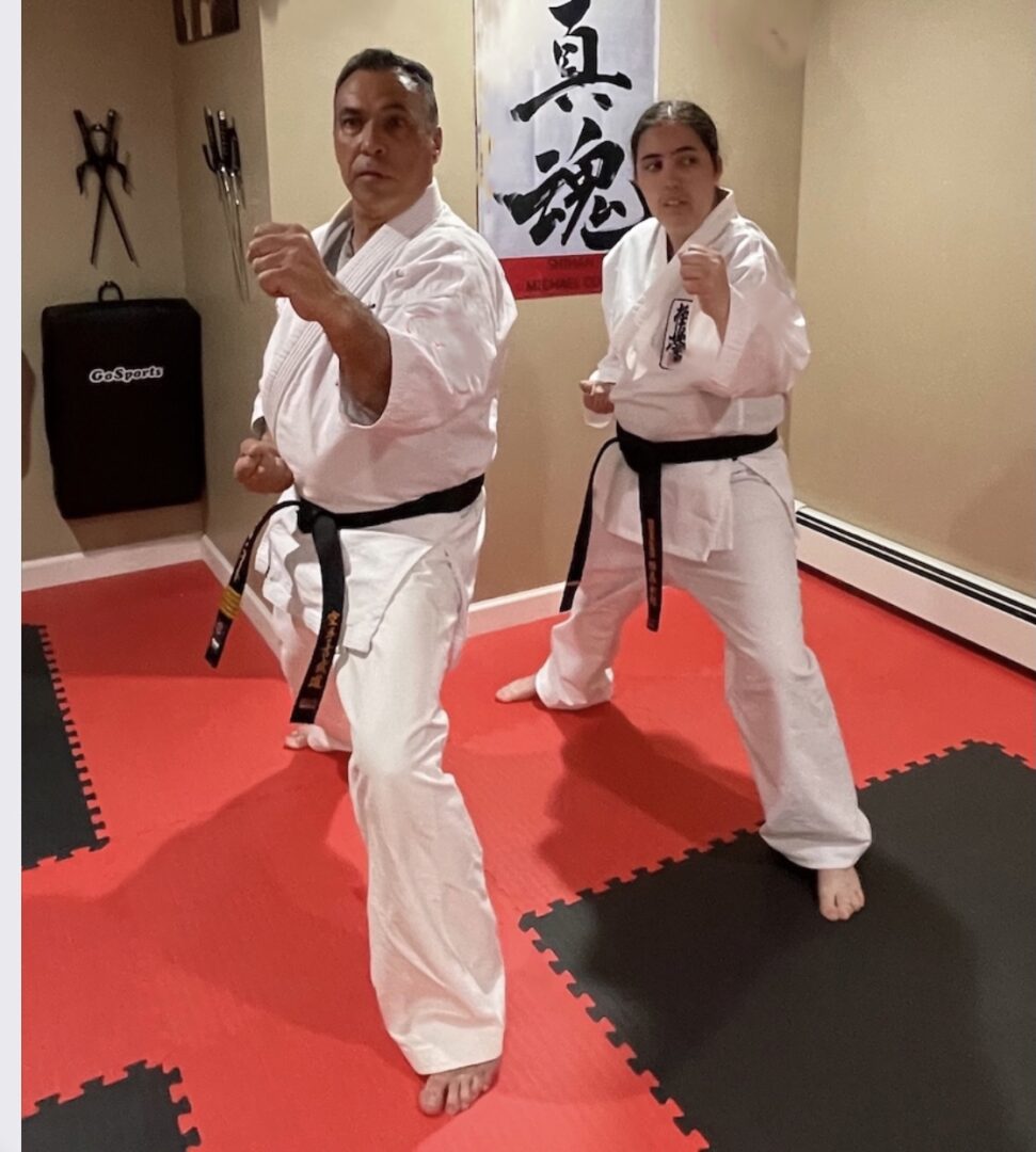 Two people in white uniforms practicing karate moves.